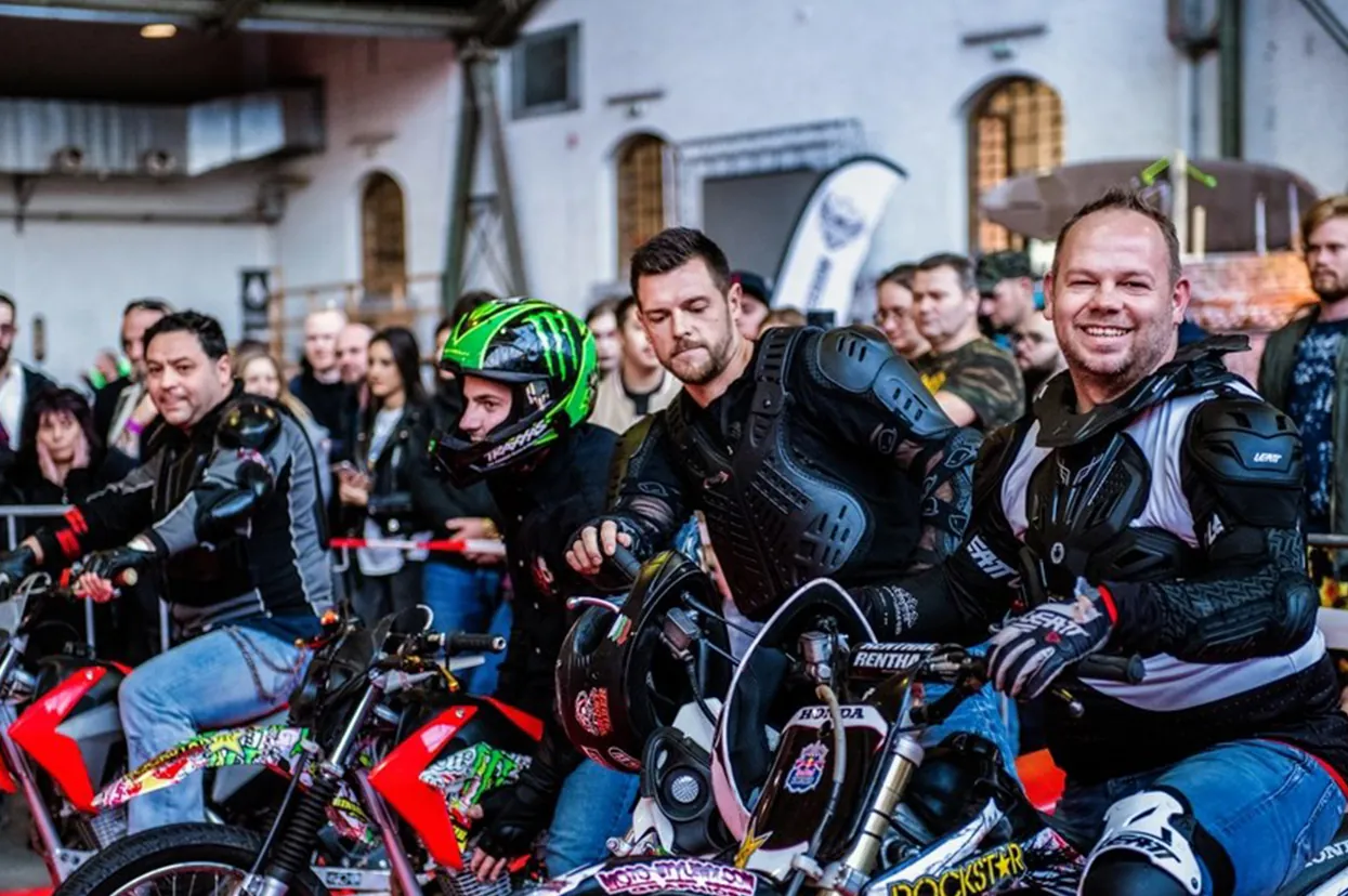 Riders and custom motorcycles lined up indoors