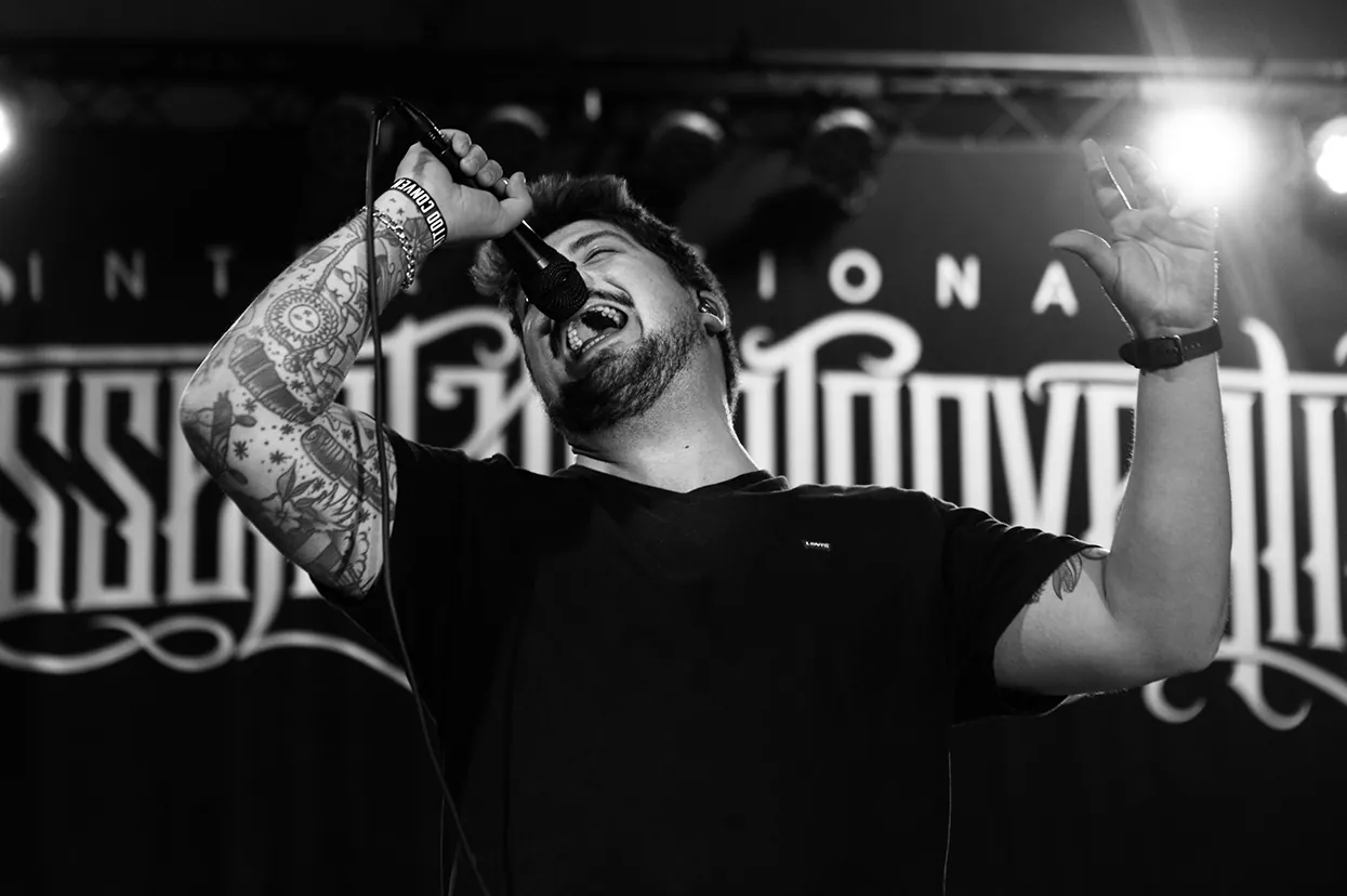 Vocalist mid-set in black and white under a spotlight