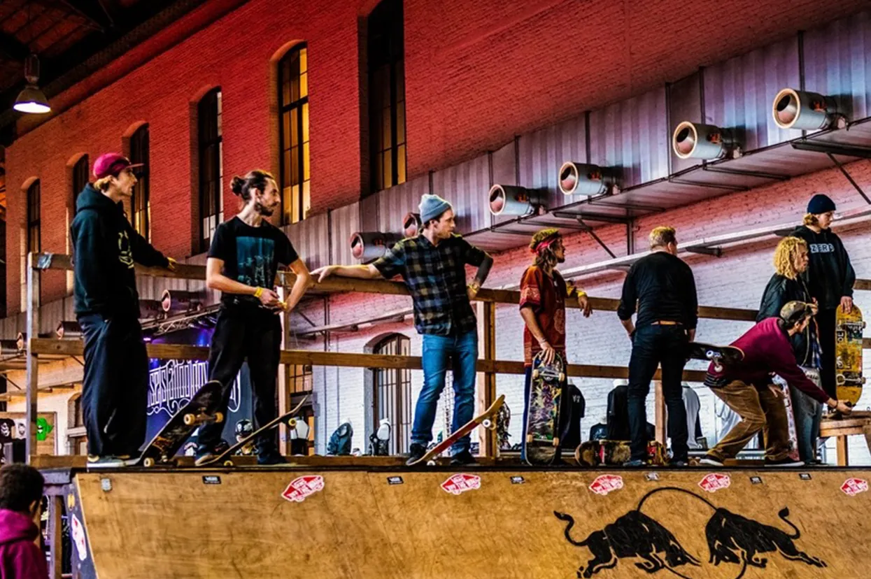 Riders lined up on top of a ramp against a brick wall
