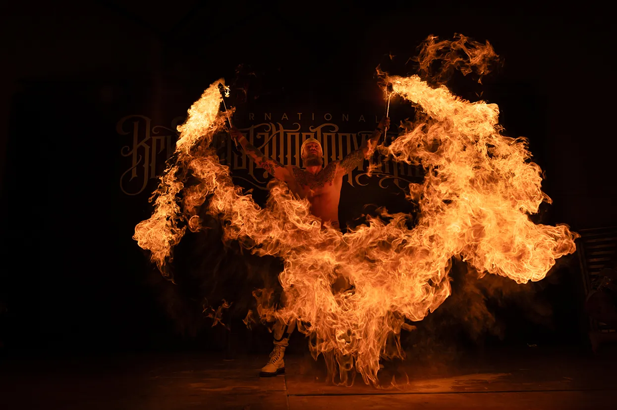 Fire breather sending a plume of flame across a dark stage